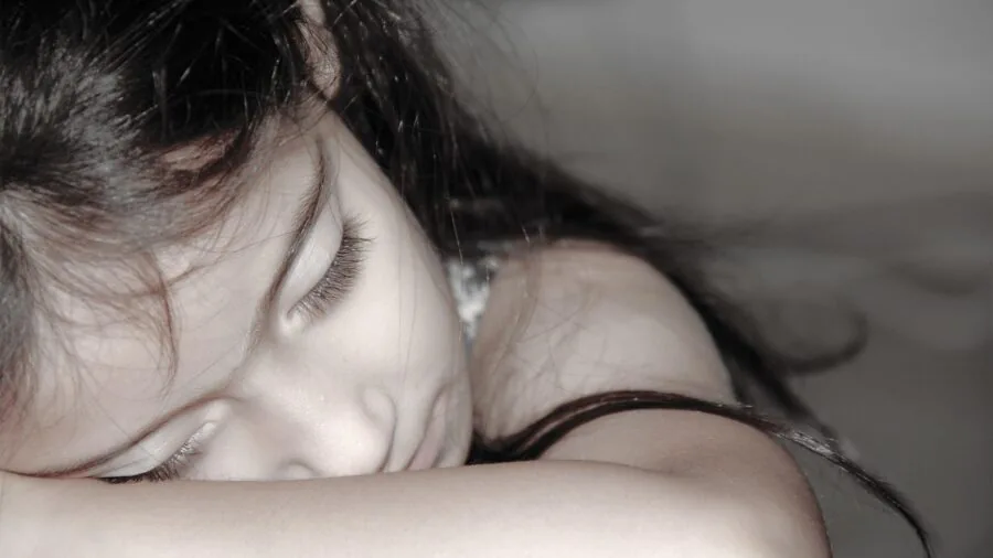 Person sleeping peacefully in bed at night with soft lighting in bedroom