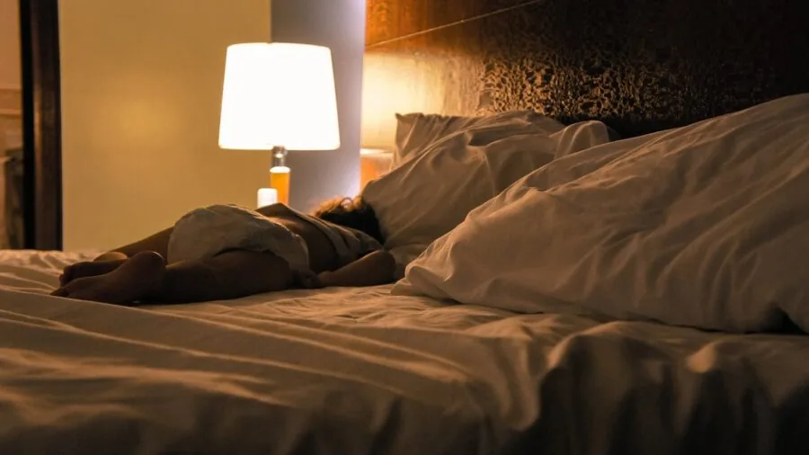 Person sleeping peacefully on breathable cotton bedding in a bright, airy bedroom