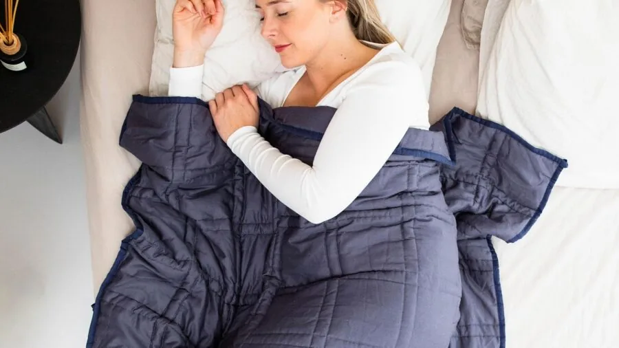 Person sleeping peacefully under a weighted blanket in natural morning light