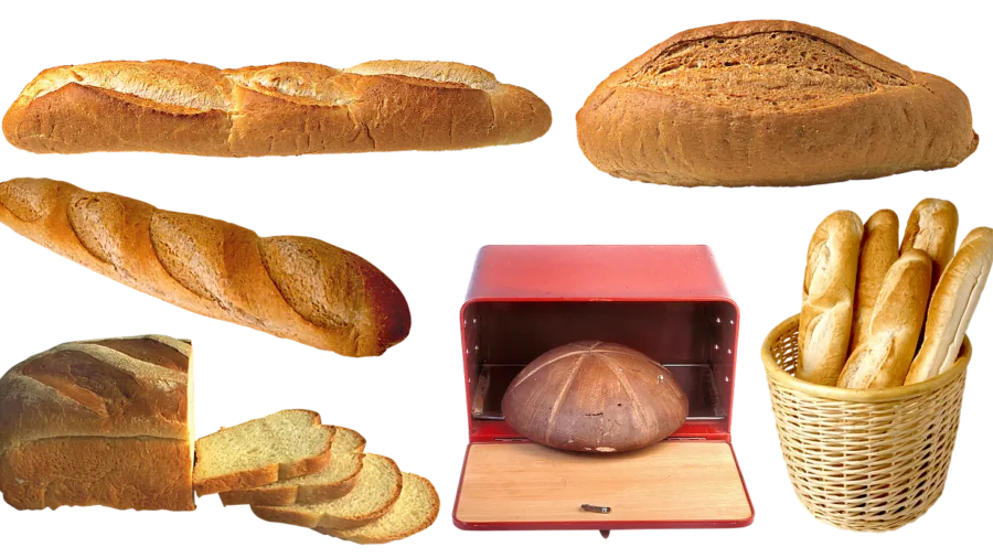 Person slicing fresh homemade bread on wooden cutting board in bright kitchen