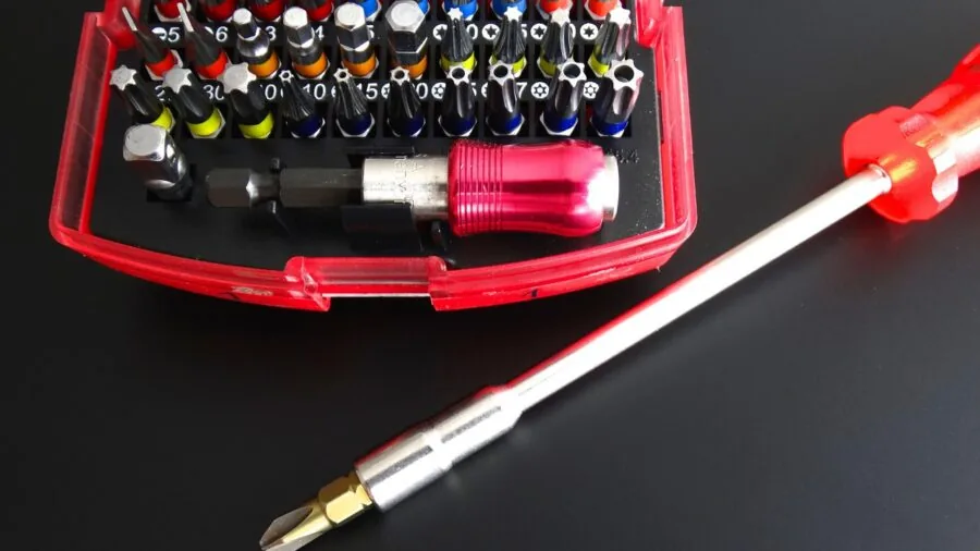 Person sorting and organizing various screwdriver bits and accessories in a home workshop setting