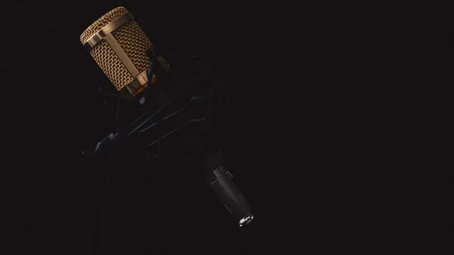 Person speaking into microphone during home recording session with acoustic treatment visible