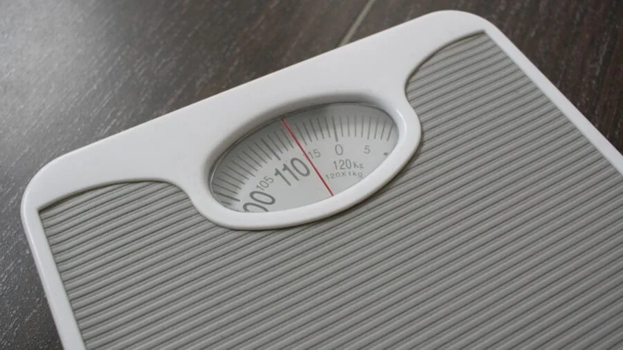Person standing on bathroom scale checking weight during morning health routine