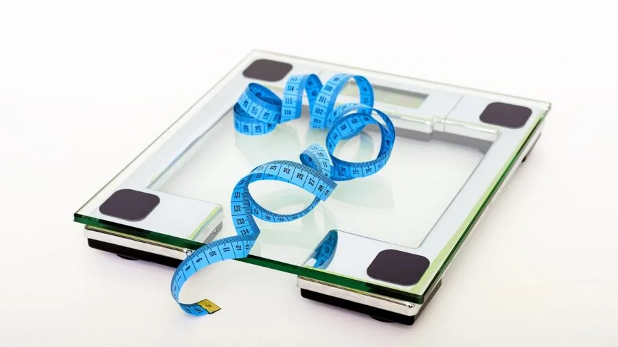 Person standing on bathroom scale monitoring body composition and health metrics at home