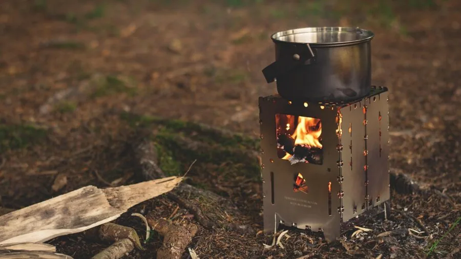 Person stirring food in a pot while camping in nature, demonstrating proper utensil handling