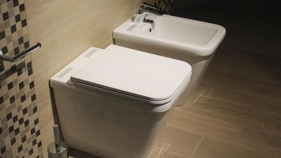 Person struggling to assemble bathroom storage cabinet with tools and instructions visible
