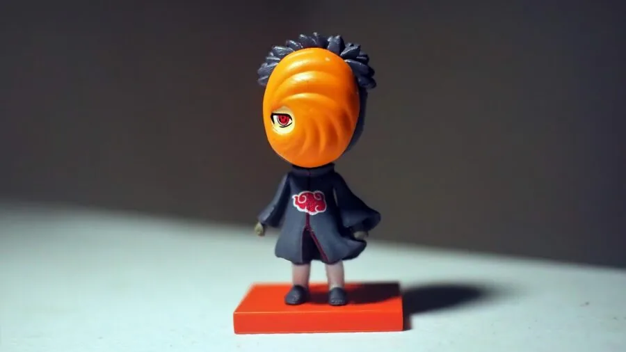 Person thoughtfully arranging collectible figurines and items on shelf, considering size and spacing