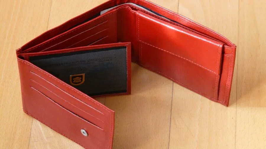 Person thoughtfully examining wallets while shopping, considering price and quality options