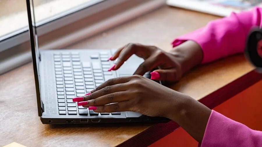 Person typing on keyboard at desk with focused hand position and proper posture