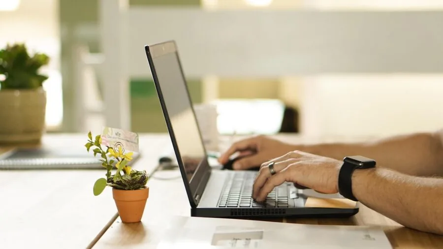 Person typing on mechanical keyboard at wooden desk with natural lighting