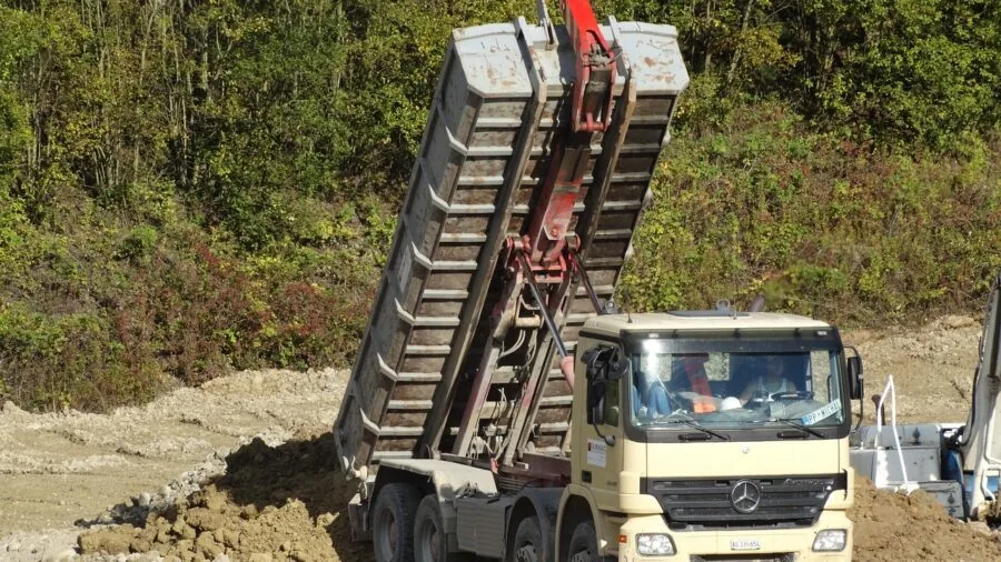 Person unloading soil or mulch from garden cart using lever mechanism