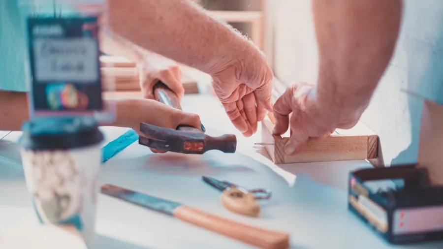 Person using a cordless glue gun for a DIY craft project on a wooden workbench