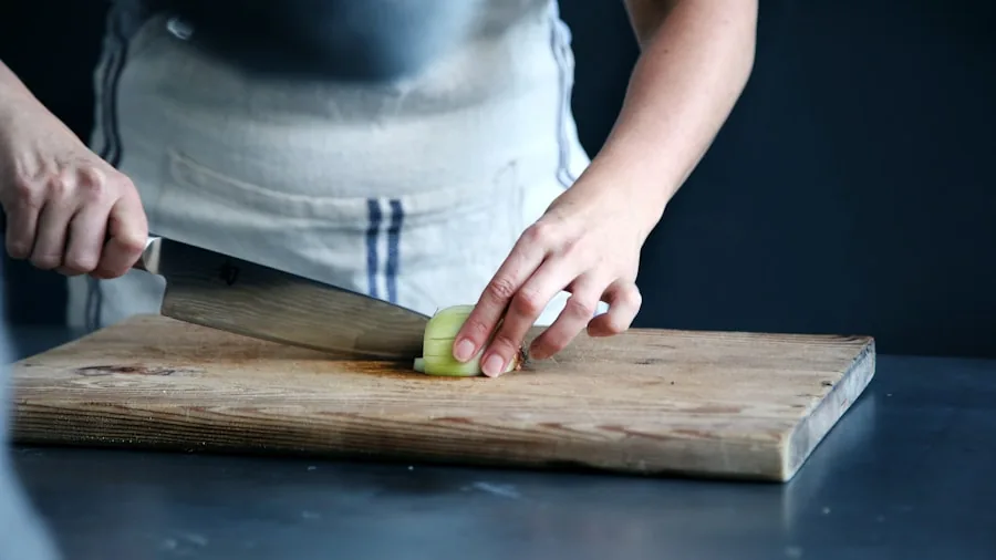 Person using a sharp knife to slice fresh vegetables on a cutting board in a home kitchen