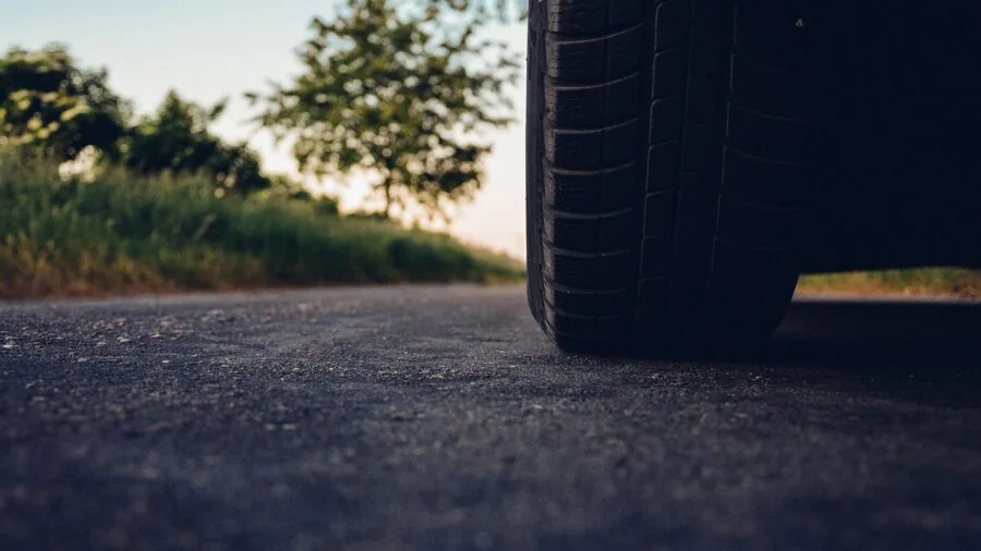Person using air compressor to inflate a car tire in a driveway or outdoor setting