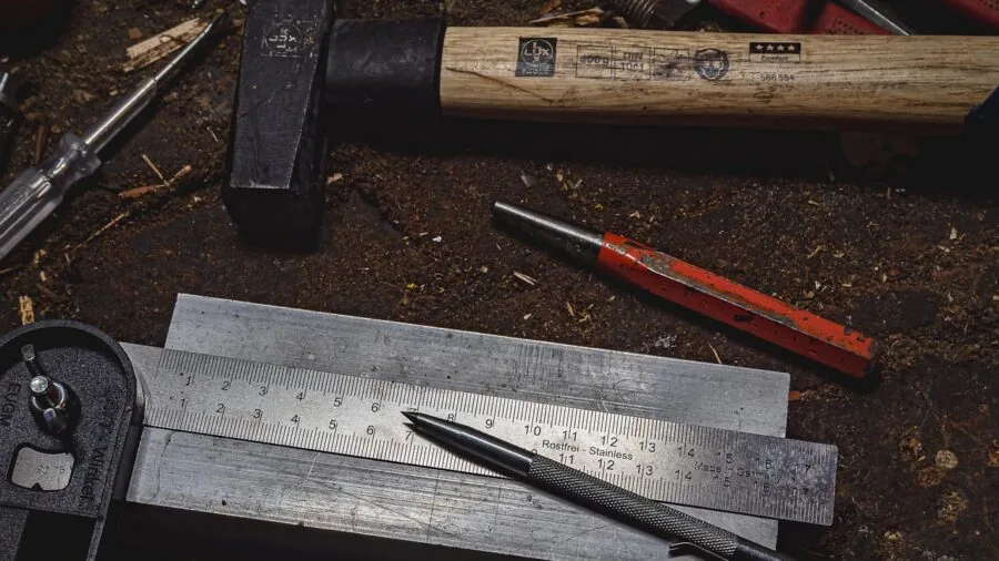 Person using digital calipers to measure 3D printed parts on workbench with tools