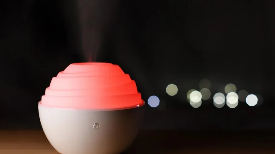 Person using essential oil diffuser in a calm home environment with natural lighting and relaxation elements