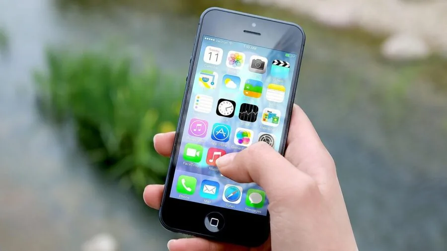 Person using smartphone app to monitor pet care remotely, hand holding phone with app interface visible