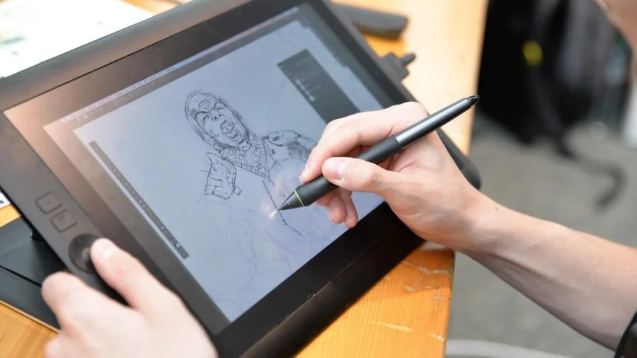Person using stylus on tablet for digital art in creative workspace