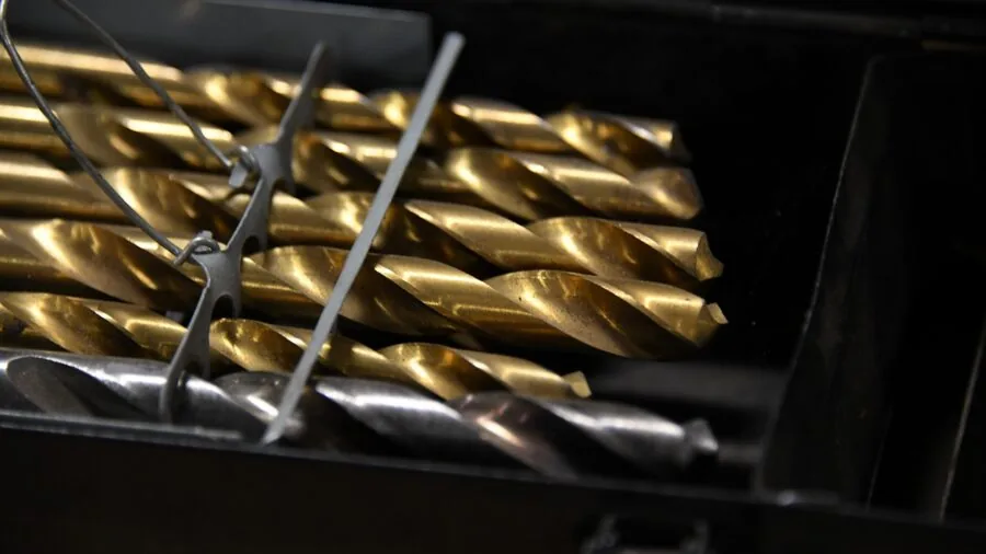 Person using tools to loosen metal bolts and fasteners in a workshop setting