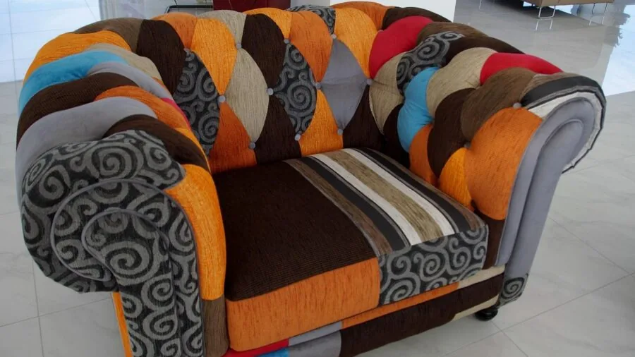 Person using upholstery attachment to clean fabric couch in bright living room