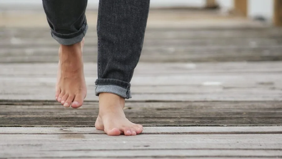 Person walking barefoot on wooden deck, demonstrating outdoor comfort and stability on smooth surface