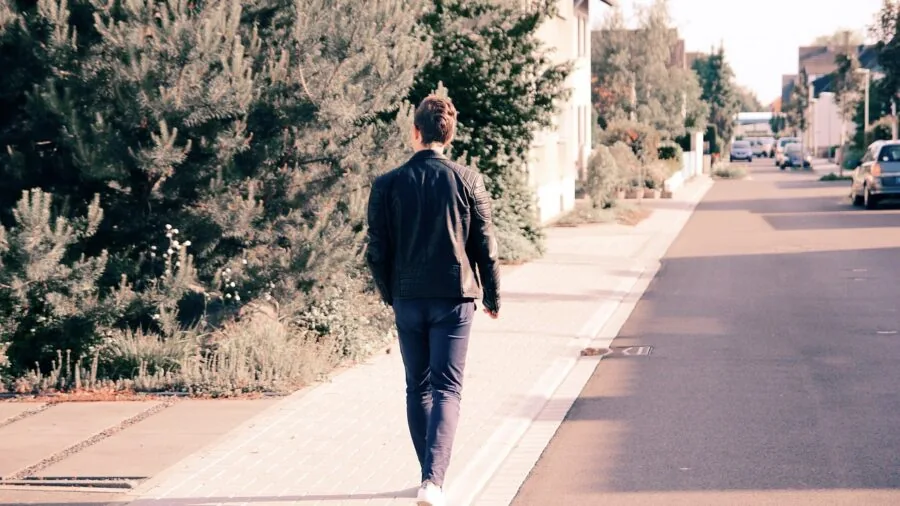 Person walking calm dog on leash through quiet residential street during daytime