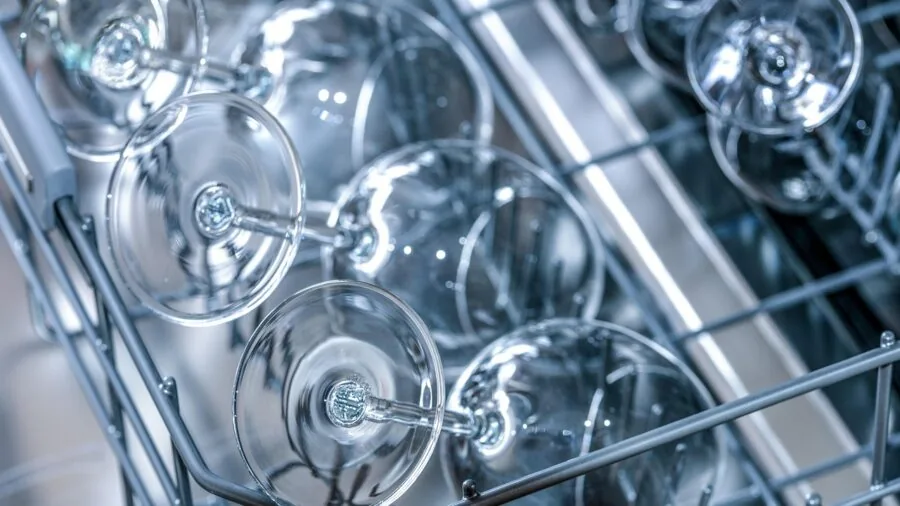 Person washing and cleaning kitchen equipment in modern home kitchen sink