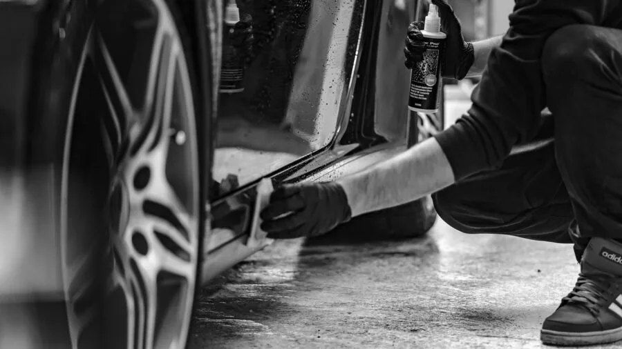 Person washing car in enclosed garage with natural light