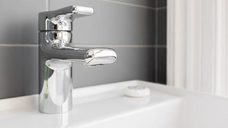 Person washing hands at bathroom sink with natural light streaming through window
