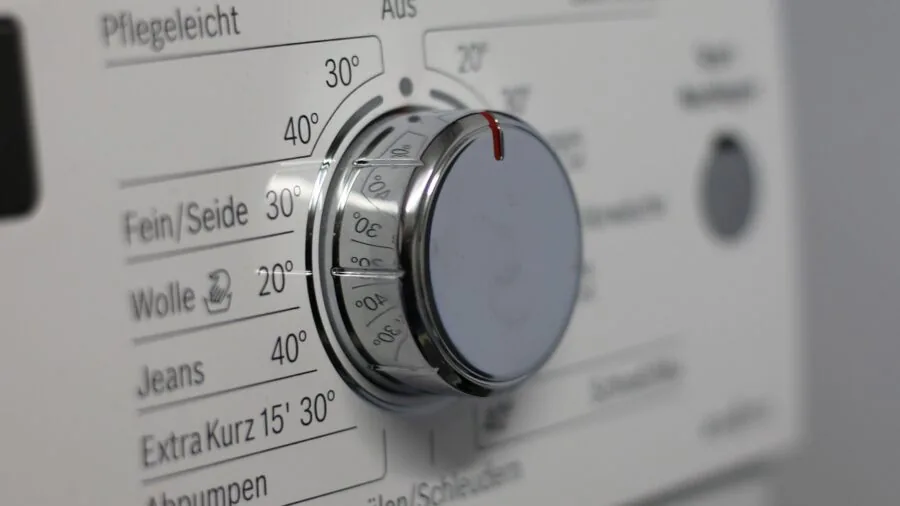 Person washing white bed linens in washing machine, emphasizing fabric care and hygiene practices