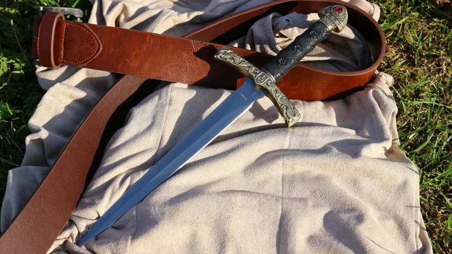 Person wearing leather knife sheath on belt during outdoor hunting adventure in natural setting