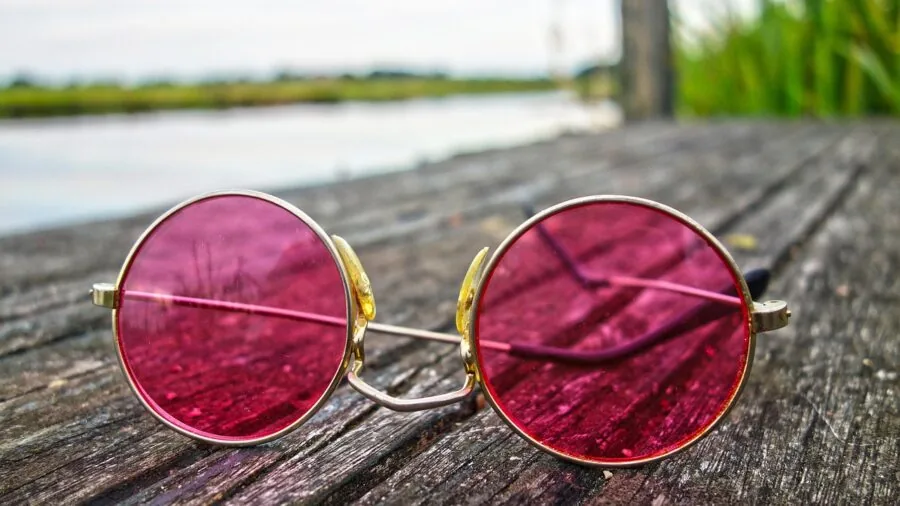 Person wearing metal frame sunglasses in outdoor natural setting, lifestyle scene
