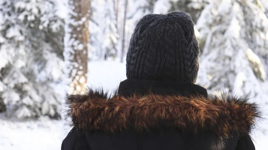 Person wearing multiple layers of warm clothing while preparing for outdoor winter activity