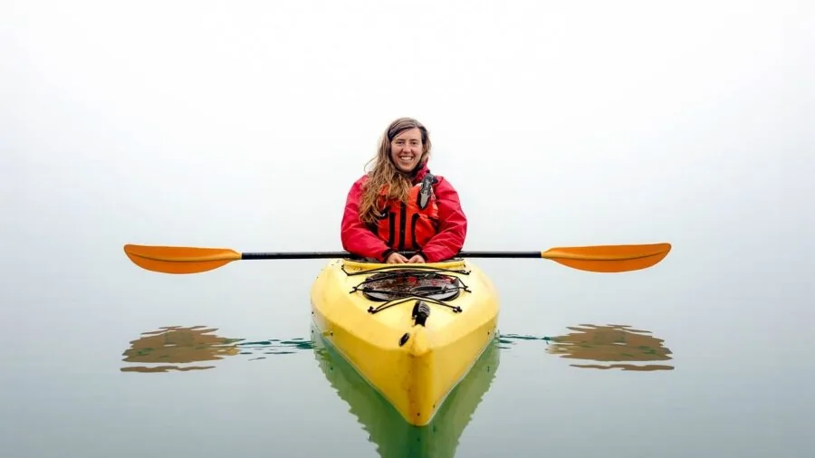 Person wearing orange life jacket on boat during water activity, demonstrating proper PFD usage