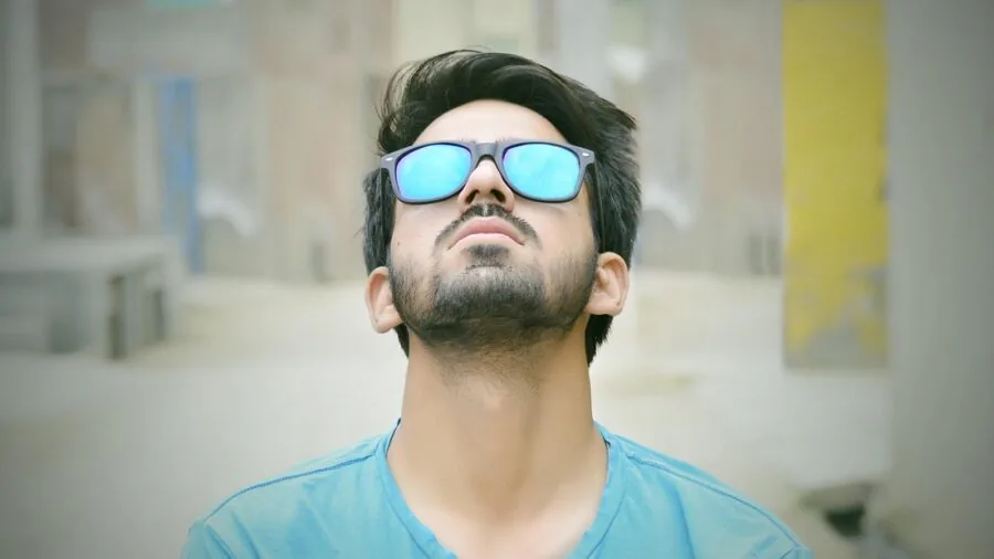 Person wearing sunglasses enjoying outdoor water activities with clear blue sky and natural sunlight