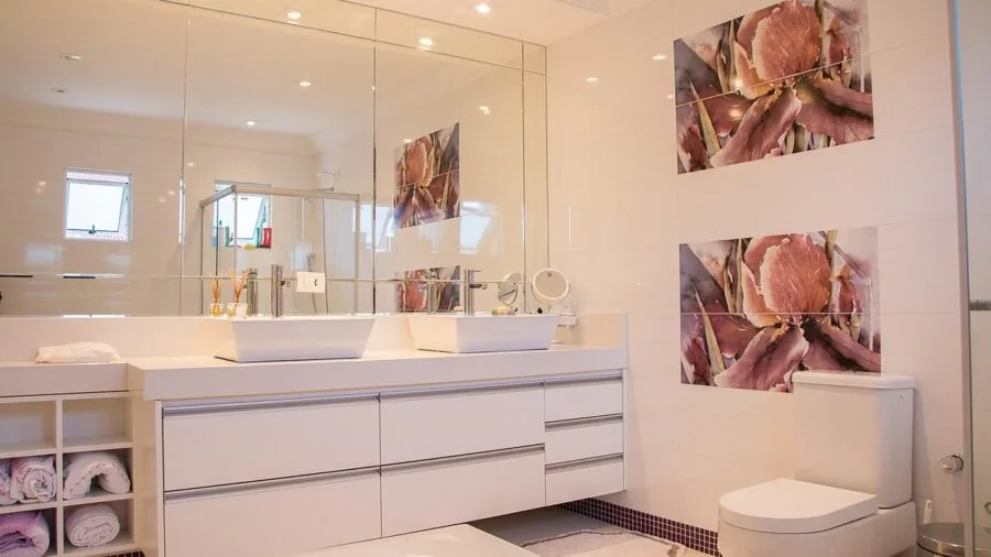 Person wiping bathroom mirror with squeegee in bright bathroom setting