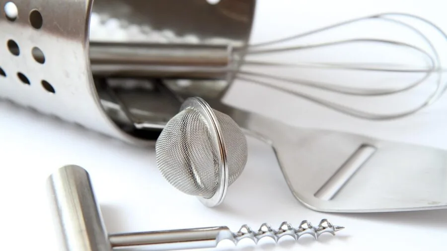 Person wiping clean stainless steel cookware in bright kitchen, demonstrating easy maintenance of quality metal equipment