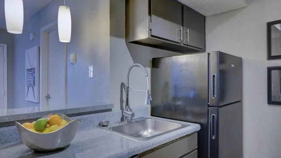Person wiping down a stainless steel kitchen counter with a cloth during meal preparation
