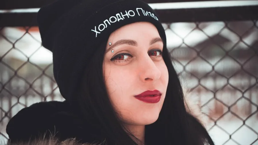 Person with natural curls wearing a beanie, smiling outdoors in natural lighting
