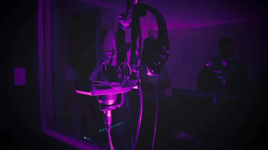 Person working at desk with microphone and audio equipment in home studio environment