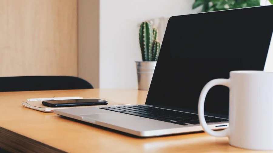 Person working at desk with smartphone charging nearby, contemporary home office setup