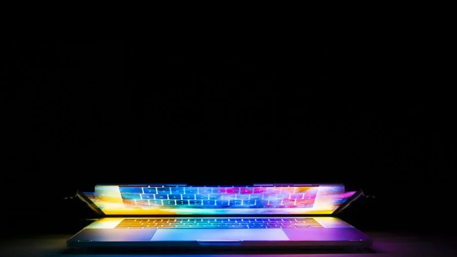 Person working at gaming desk with vibrant RGB lighting illuminating the workspace
