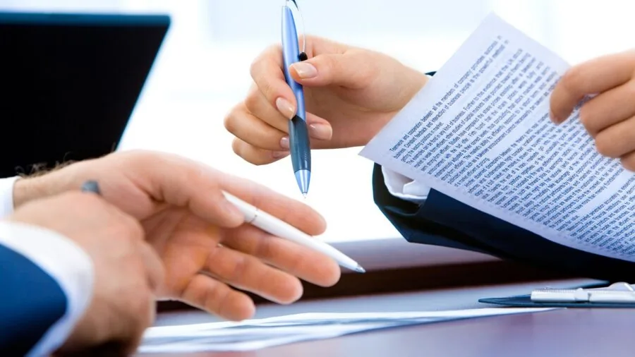 Person working at home office desk with papers and printer in background