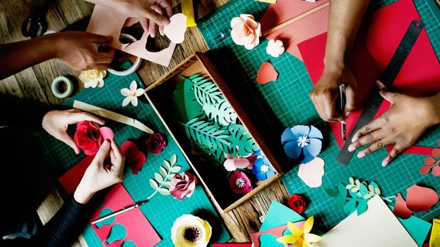 Person working on craft project at table with cutting mat and tools for precise cutting