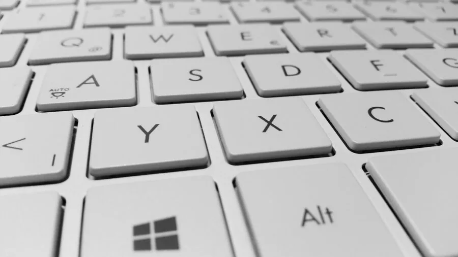Person working on laptop with multiple devices on desk, showing cross-platform compatibility and digital workflow