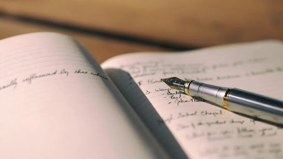 Person writing in notebook with gel pen, capturing the act of writing and ink flow in everyday use