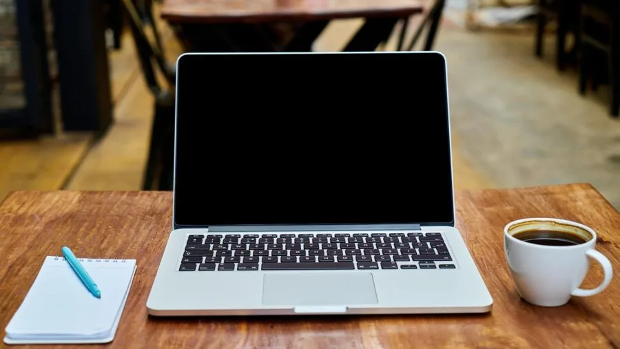 Person writing notes at desk, considering budget and value for digital tools and productivity