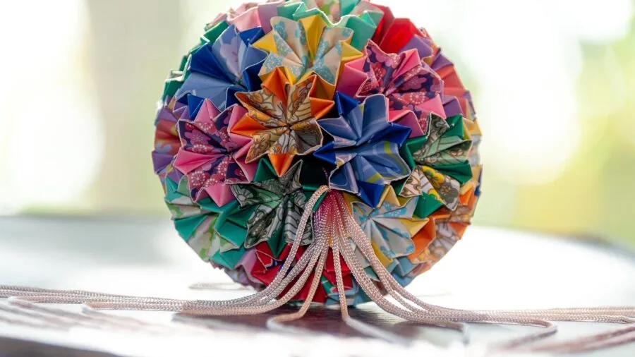 Person's hands carefully folding origami paper, demonstrating paper weight and texture quality