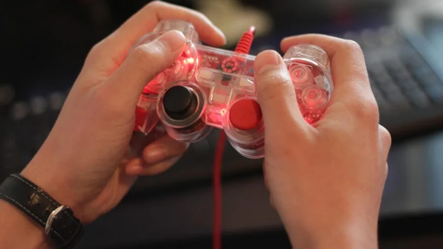 Person's hands gripping a retro gaming controller during gameplay session