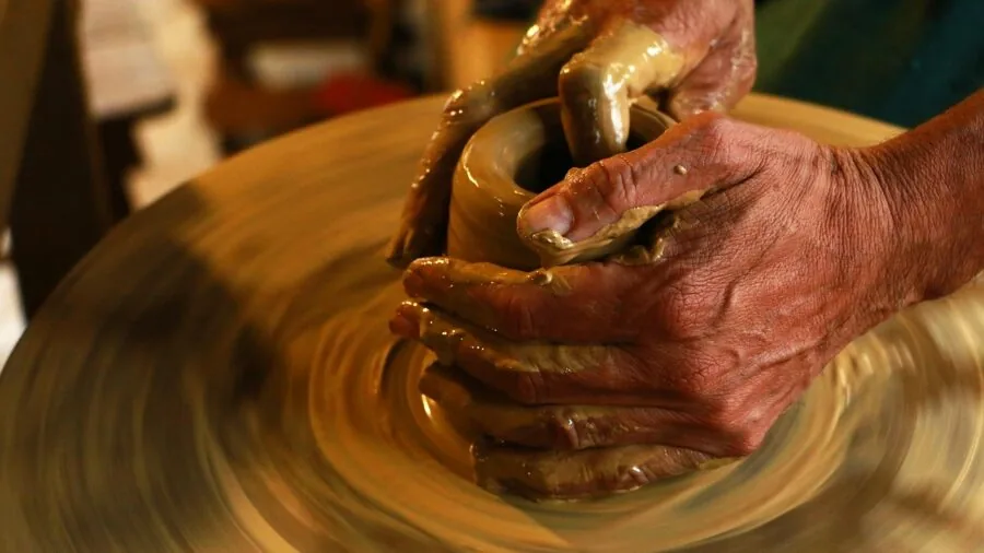 Person's hands working with different colored air dry clay materials on wooden work surface
